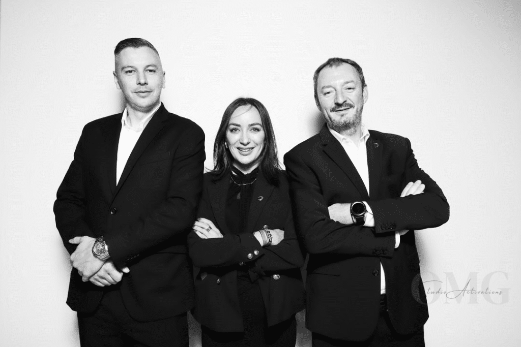 Professional group portrait in black and white featuring three individuals in elegant attire, embodying sophistication and style, suitable for luxury events and corporate galas, with OMG Studio branding visible.